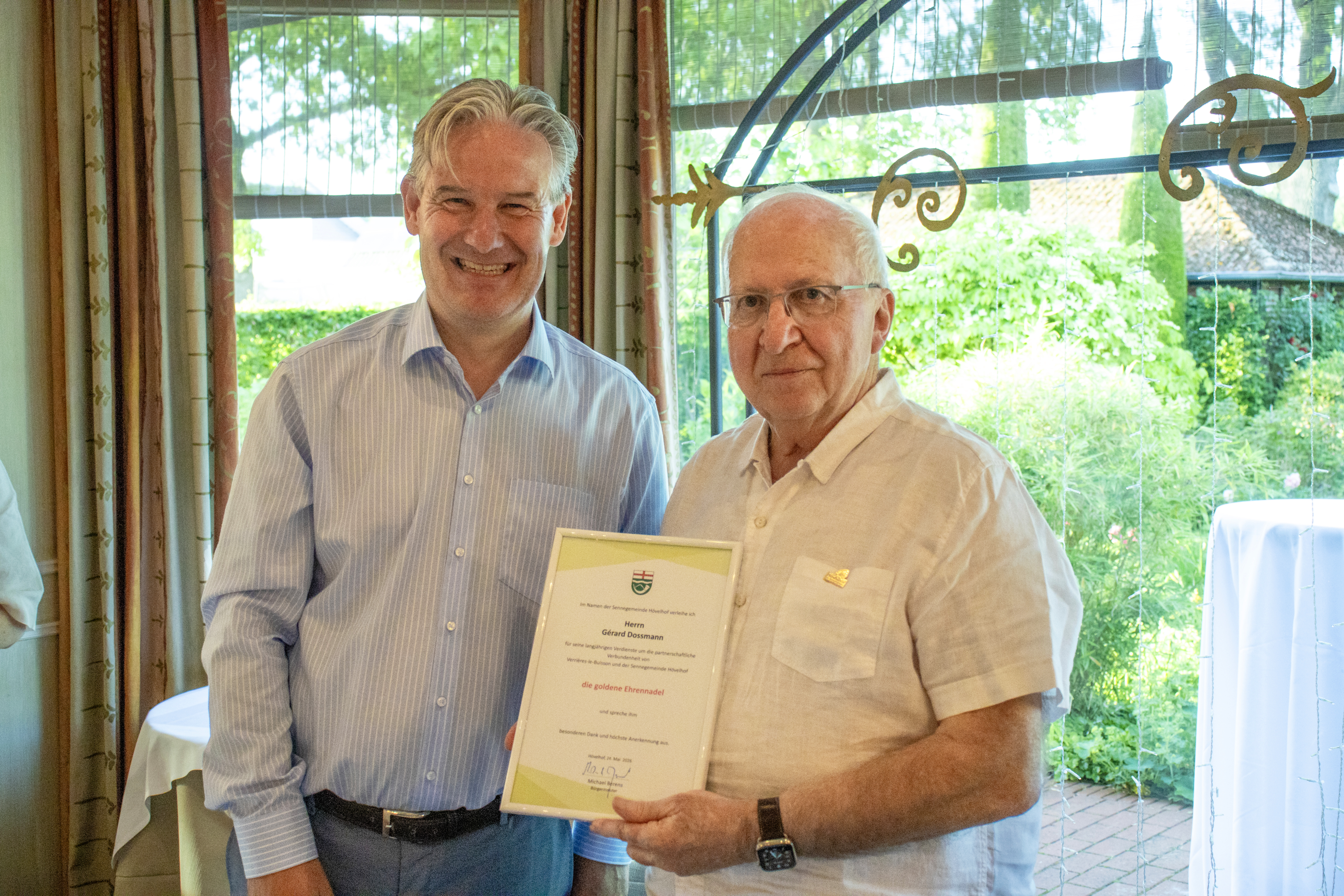 B�rgermeister Michael Berens (l.) zeichnete G�rard Dossmann mit der Goldenen Ehrennadel der Gemeinde H�velhof f�r dessen langj�hriges Engagement f�r die St�dtepartnerschaft mit Verri�res-le-Buisson aus